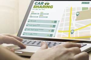 travel and trip concept: man using a laptop with car sharing software on the screen. Screen graphics are made up.